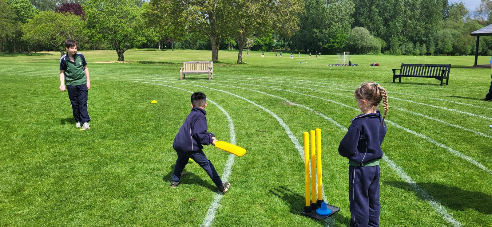 Young children practising cricket skills on school playing field