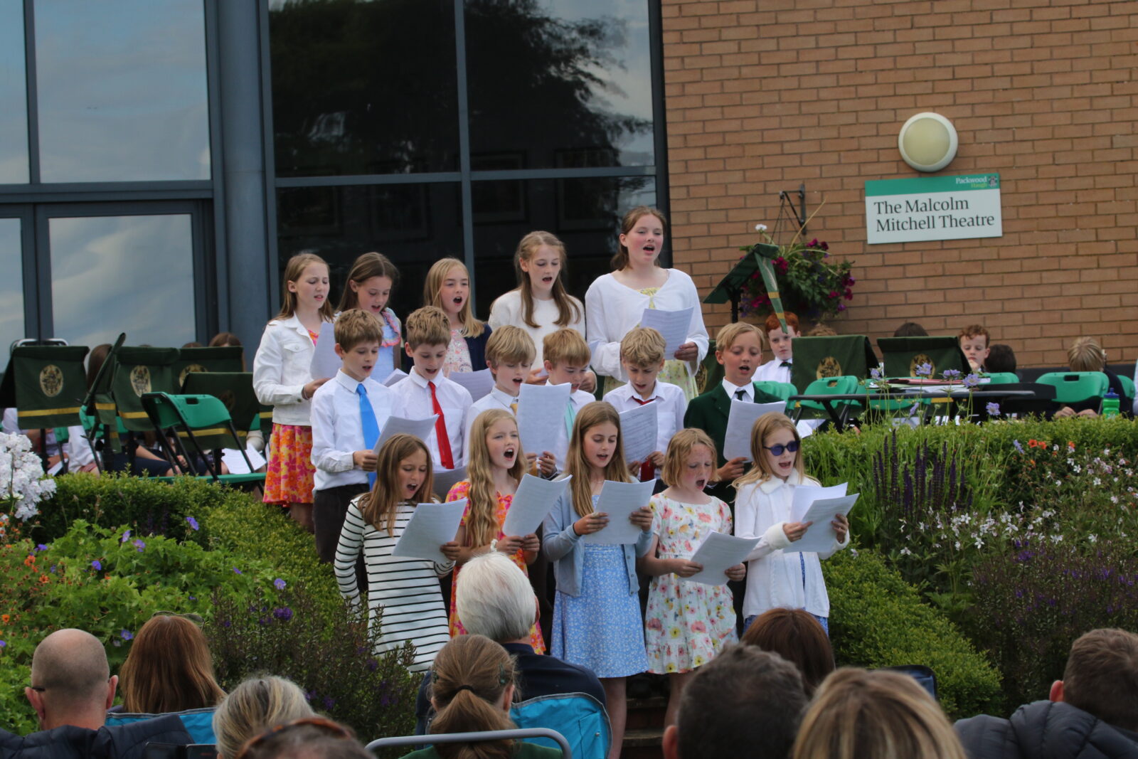 A choir of boys and girls performing school concert outdoors