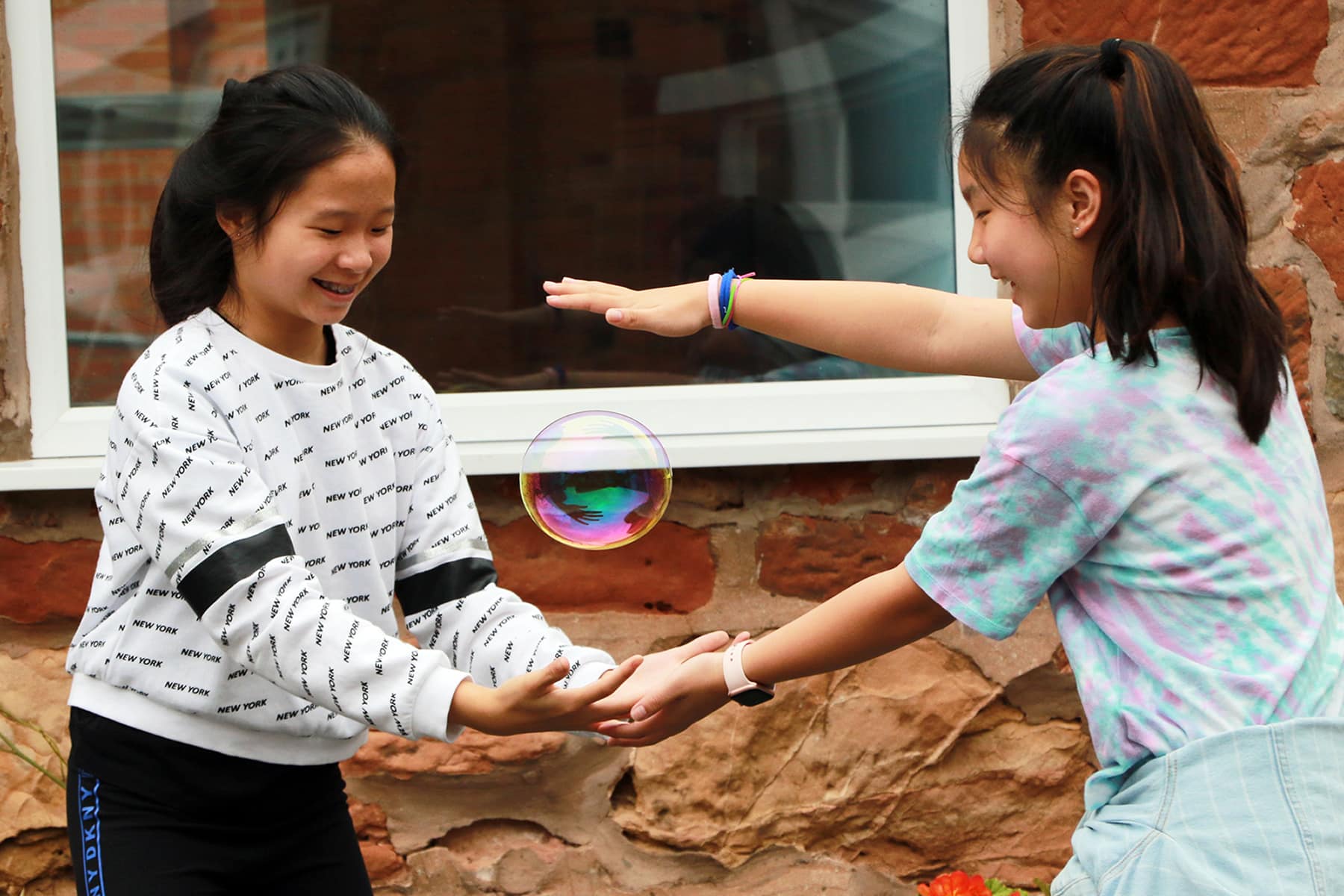 Two girls experimenting with making bubbles.