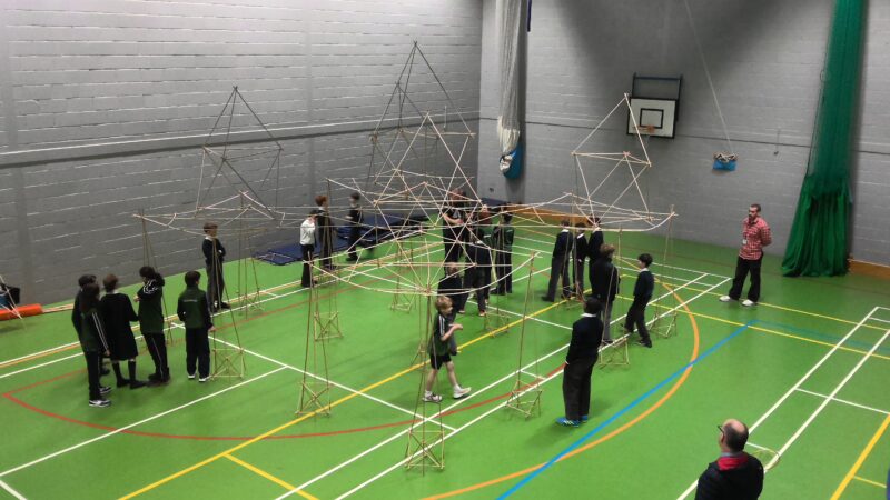 Giant structure created from bamboo sticks created by pupils in school sports hall